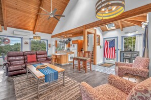 A spacious living room with a leather sofa, patterned armchairs, a wooden coffee table, and a kitchen in the background. - Lincoln City Retreat: Private Hot Tub, Game Room, Easy Beach Access (Lincoln City)