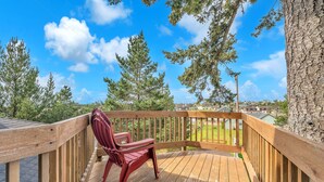 A wooden deck with a red chair, surrounded by trees and a clear sky. - Pacific City Oasis: Ocean Views, Game Room & Walk to Bob Straub Park (Pacific City)