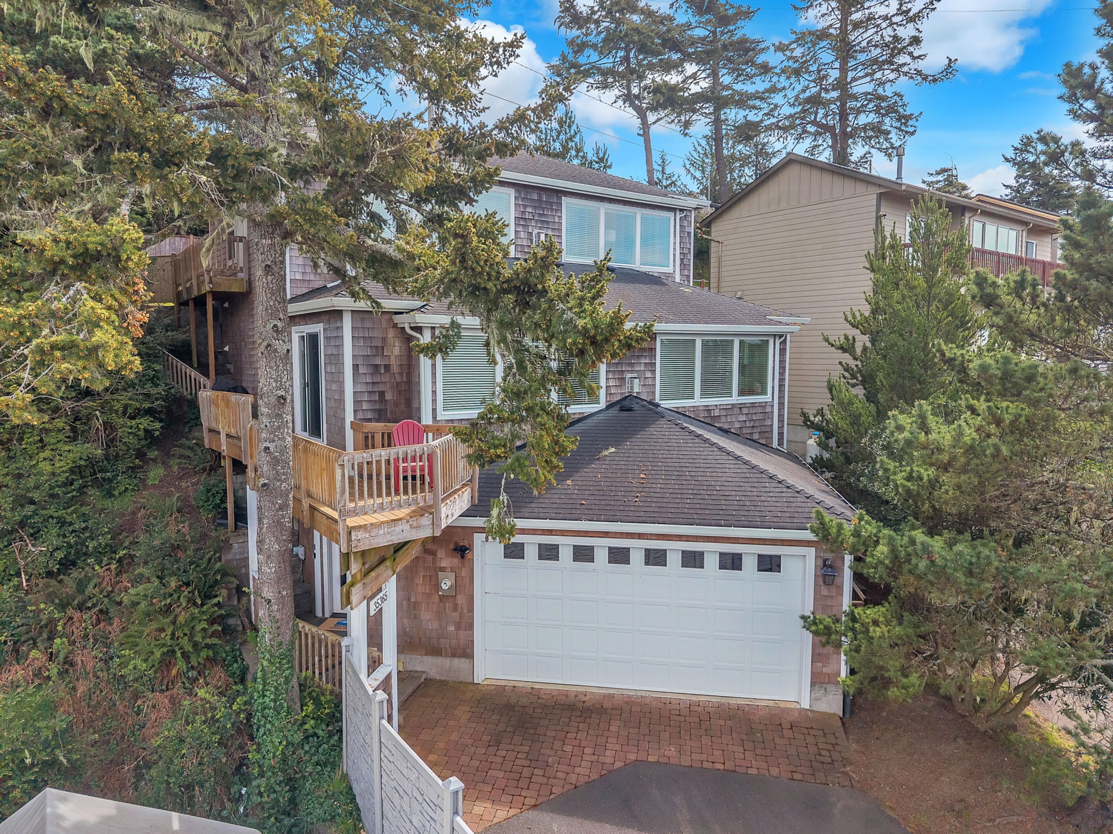 Multi-level coastal home nestled among mature trees with garage and deck space in a peaceful wooded neighborhood.