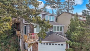 A two-story house with a garage, a balcony, and a wooden deck. - Pacific City Oasis: Ocean Views, Game Room & Walk to Bob Straub Park (Pacific City)