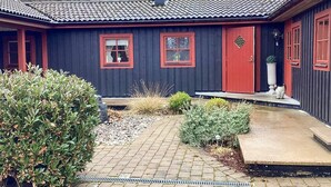 A house with a dark exterior, red-framed windows, a red door, and a tiled roof. - 4 Star Holiday Home in Eldsberga (Eldsberga)