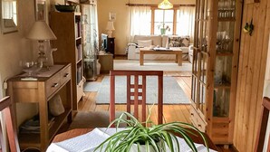 A cozy living room with a sofa, a coffee table, and a dining table with a potted plant. - 4 Star Holiday Home in Eldsberga (Eldsberga)