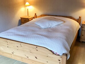 A bed with a wooden headboard, a white quilt, and a bedside table with a lamp. - 4 Star Holiday Home in Eldsberga (Eldsberga)