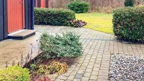 A red building with a paved entrance, surrounded by well-maintained hedges and a grassy yard. - 4 Star Holiday Home in Eldsberga (Eldsberga)