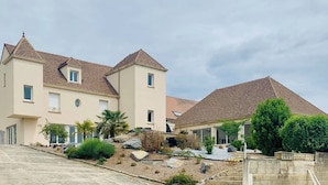 Ein zweigeschossiges Wohnhaus mit Ziegeldach, Auffahrt und gepflegtem Garten mit Steinen und Pflanzen.