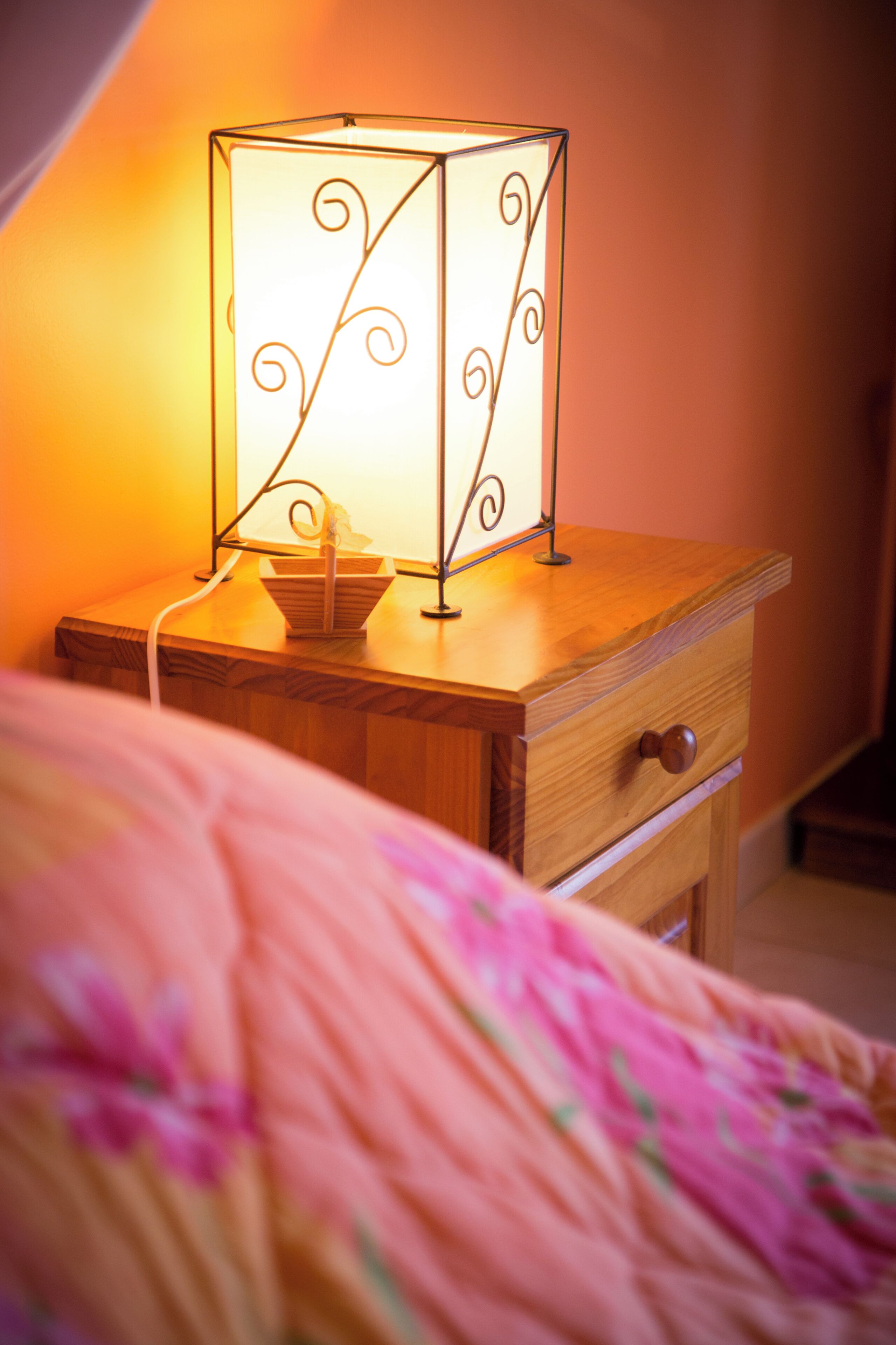 Ein Nachttisch mit Lampe, Schublade und Korb.
