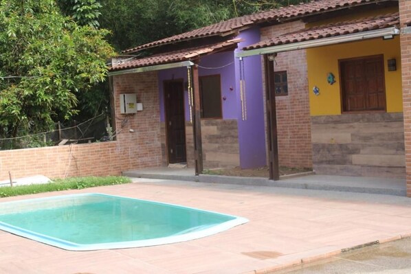 A residential property with a swimming pool, a brick exterior, and a purple wall.