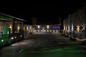 An outdoor area with a paved walkway, illuminated by multiple light sources.