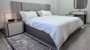 Une chambre à coucher moderne avec un lit, des tables de chevet, une commode, un miroir et un tapis.