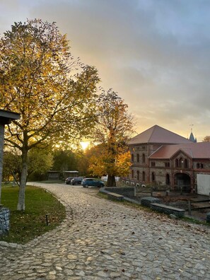 A cobblestone street leading to a historic building with a red roof and arched windows. - Modern Studio With sun Terrace and Barrel Sauna (Grossharthau)