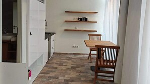 Une cuisine moderne avec des meubles blancs, une table à manger en bois et un luminaire suspendu.