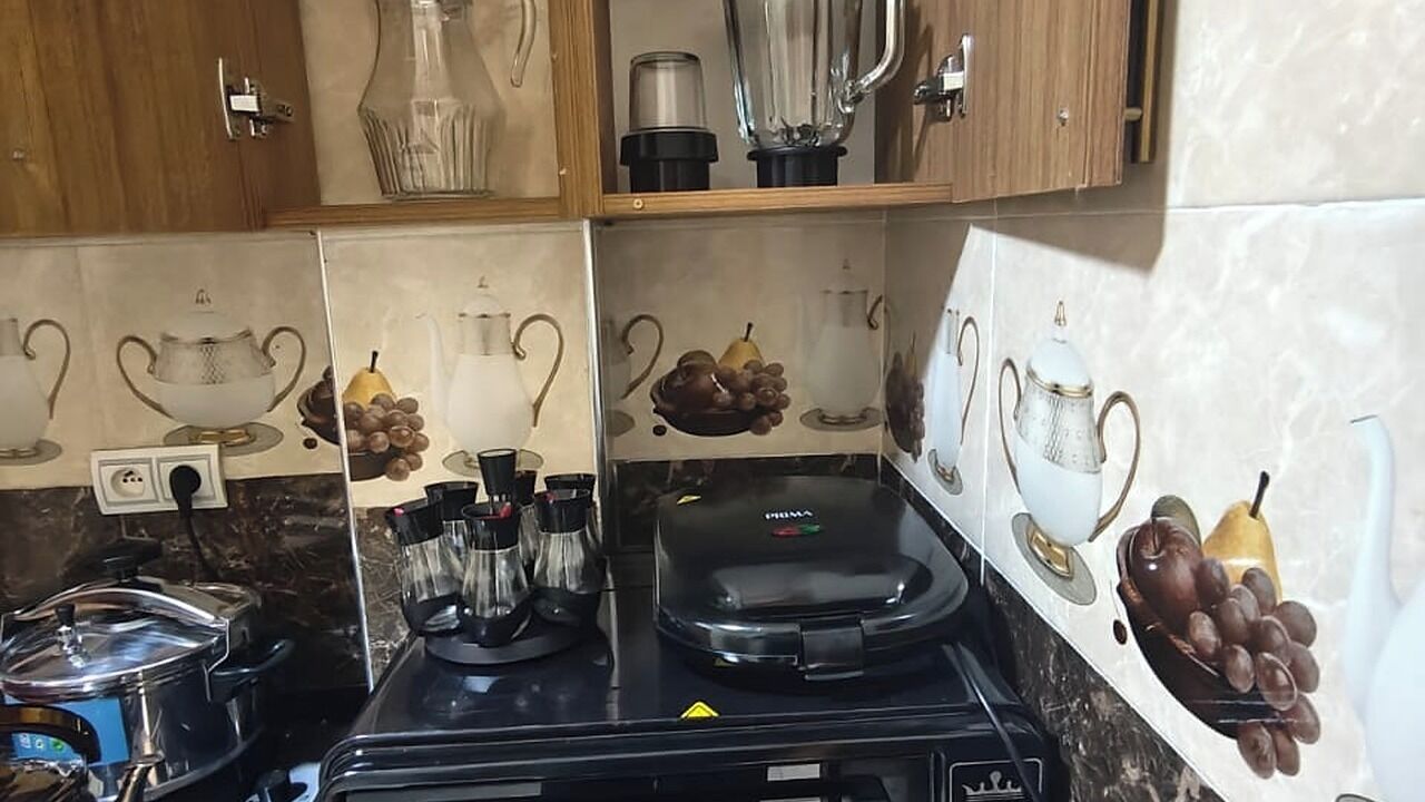 A kitchen with a stove, a coffee maker, and a blender on the countertop.