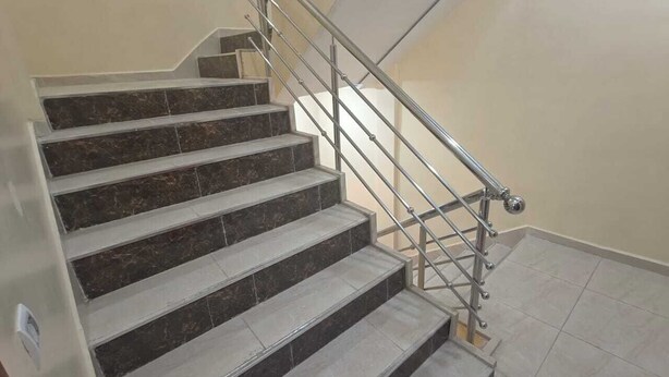 Un escalier avec des marches en marbre et une rampe métallique.