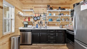 Eine kleine Küche mit Holzwänden, einem Edelstahl-Kühlschrank und einem Geschirrspüler.