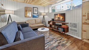 Ein gemütliches Wohnzimmer mit einer Ledersofa, einem Fernseher, einem Kamin und einem Bücherregal.
