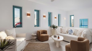 Een moderne woonkamer met een witte bank, een bruine fauteuil, een ronde salontafel en een plafondventilator.