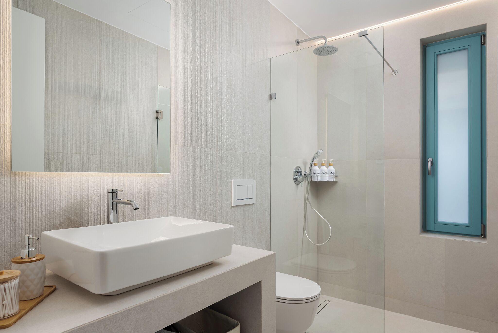 A modern bathroom with a large rectangular sink, a glass shower enclosure, and a toilet.