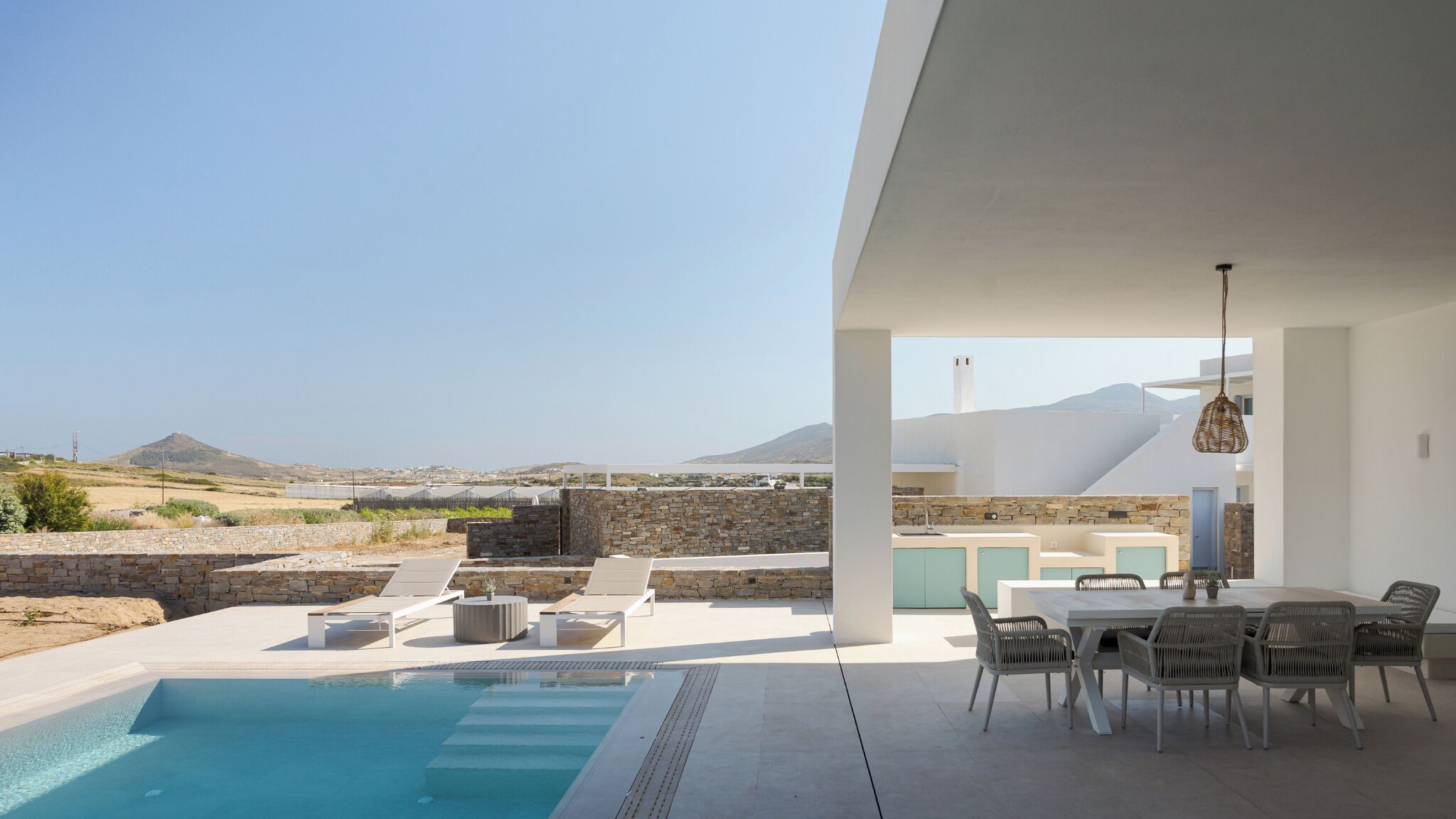 A modern outdoor pool area with a view of the landscape and mountains.