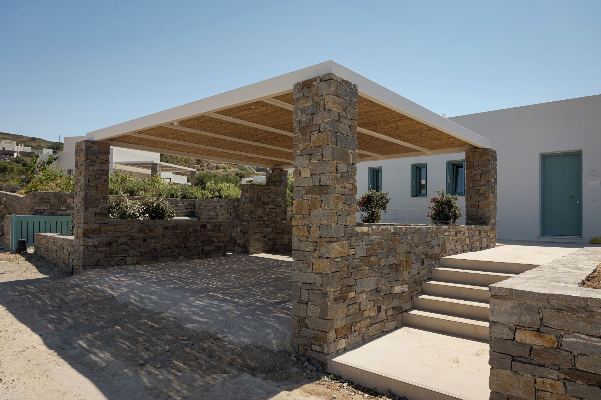 A modern building with a stone facade, a covered outdoor area, and a staircase leading to the entrance.