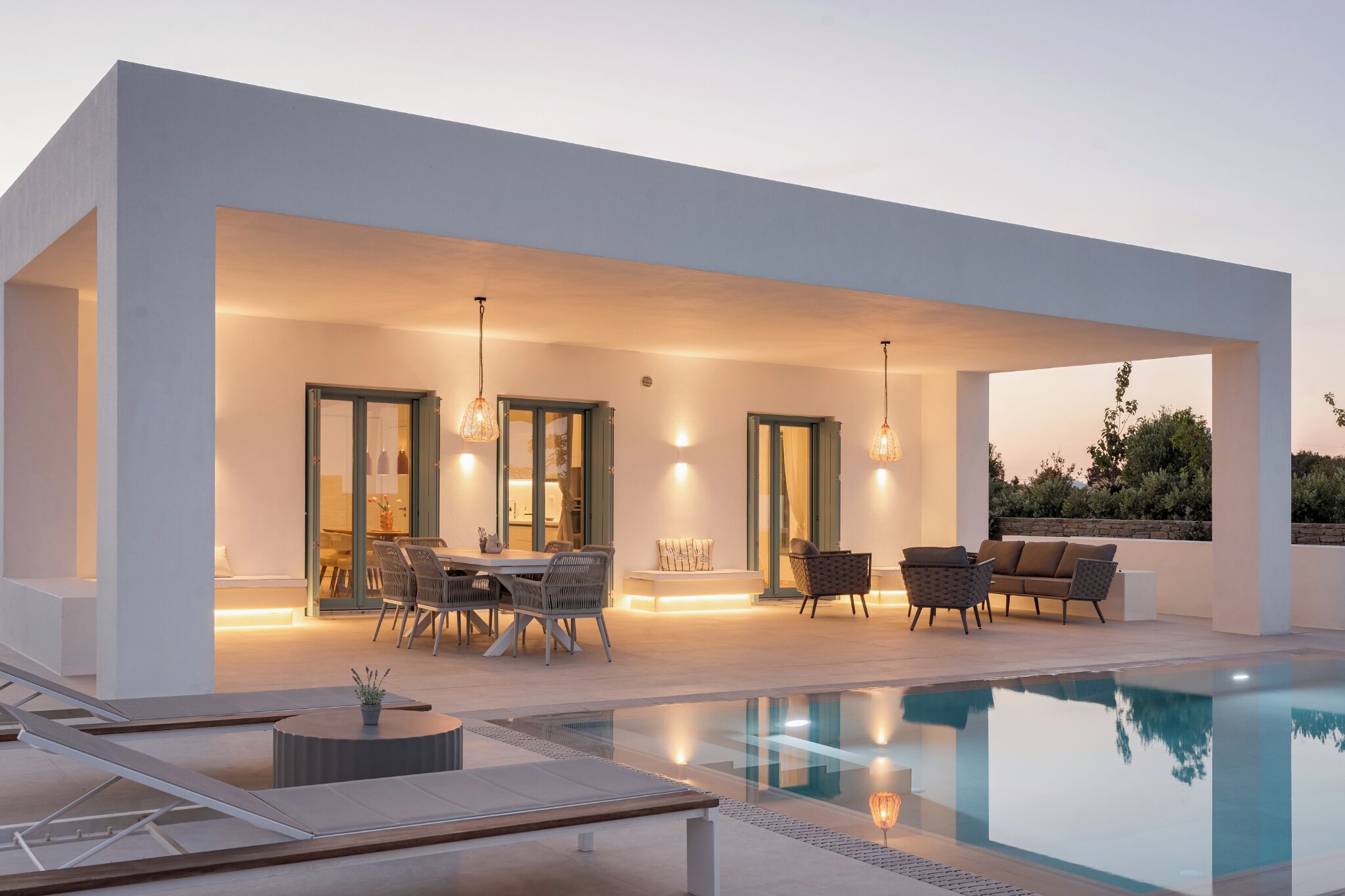A modern outdoor pool area with a dining setup, lounge chairs, and a clear view of the pool.