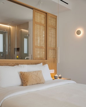 Ein Schlafzimmer mit einem großen Bett, einem hölzernen Kopfteil, einem Spiegel und einem Nachttisch mit zwei dekorativen Vasen.