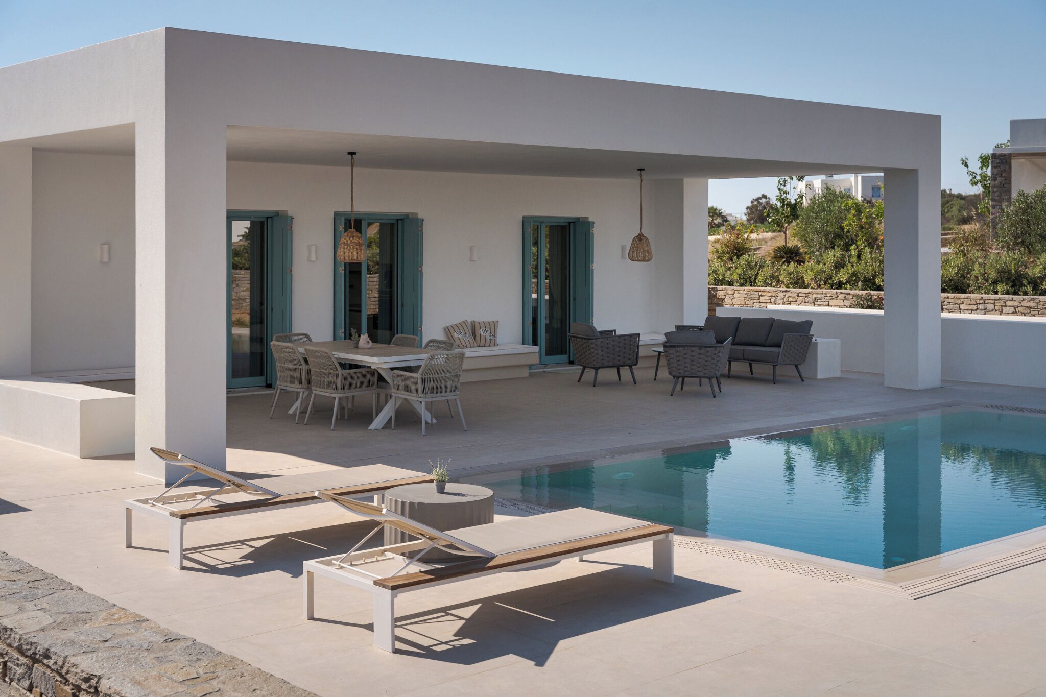 A modern outdoor pool area with lounge chairs, a dining table, and chairs.