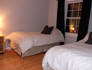 Ein Schlafzimmer mit zwei Betten, einem Nachttisch und einem Fenster mit Vorhängen.