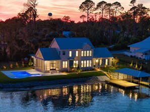 Une grande maison avec une piscine, un quai et un château d’eau en arrière-plan.