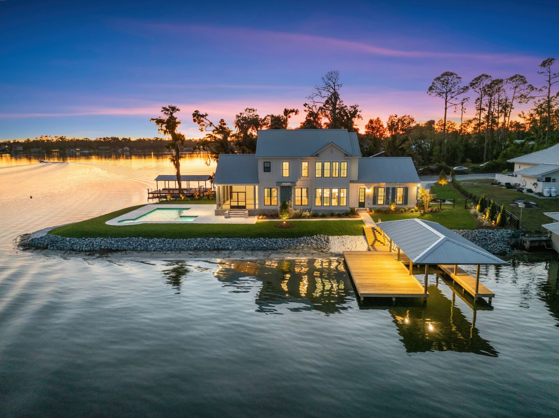 Une propriété située au bord de l’eau, comprenant une grande maison, une piscine et un quai.