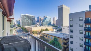 Paesaggio urbano con edifici moderni, cielo sereno e un balcone con vista sulla città.