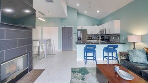 Una cucina moderna con mobili bianchi, una grande isola e sgabelli da bar blu.