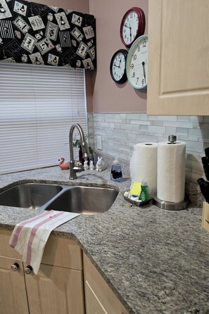 A kitchen with a double sink, a faucet, a swan-shaped soap dispenser, paper towels, and a bottle of dish soap. - Spacious 4-bedroom villa in peaceful Kissimmee private pool minutes from Disney (Kissimmee)