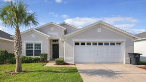 A single-story house with a front garage, a palm tree, and a well-maintained lawn. - Disney 10 mins private house privacy screen pool, gated community no resort fees (Kissimmee)