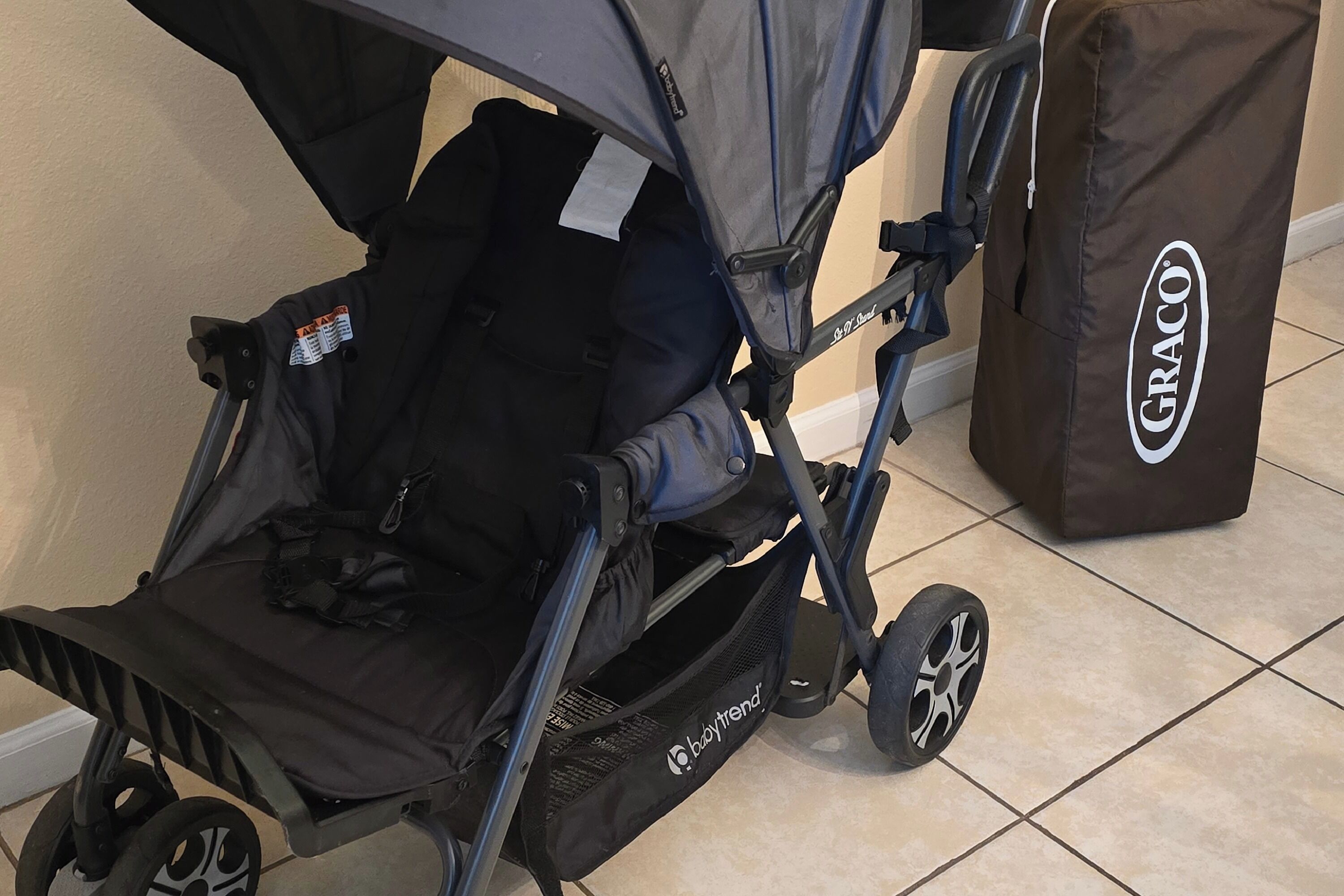 A stroller with a brand label, a bag with a brand label, and a tiled floor.