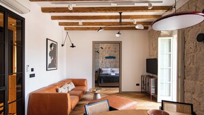 A modern living room with a sofa, a dining table, and a television. - Santa Croce Suite by DuHomes (Dubrovnik)