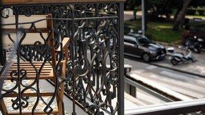 A wrought iron balcony railing with a wooden ledge and a view of a street with parked cars and a scooter. - Santa Croce Suite by DuHomes (Dubrovnik)
