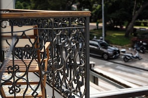 A wrought iron balcony railing with a wooden ledge and a view of a street with parked cars and a scooter. - Santa Croce Suite by DuHomes (Dubrovnik)