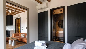 A modern hotel room with a bed, a sofa, a small table, and a bathroom visible through an open door. - Santa Croce Suite by DuHomes (Dubrovnik)