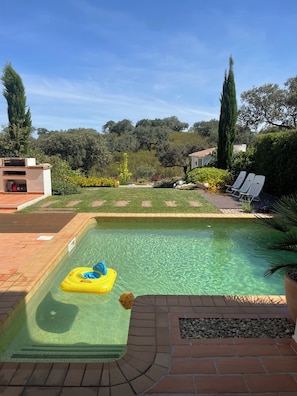 A swimming pool with clear water, a yellow inflatable float, and a brick deck.