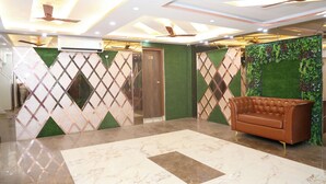 A lobby with a marble floor, a brown leather sofa, ceiling fans, and decorative panels. - Pragati Guest House (Gorakhpur)