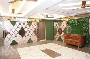 Eine Lobby mit Marmorboden, einem braunen Ledersofa, Deckenventilatoren und dekorativen Wandverkleidungen.