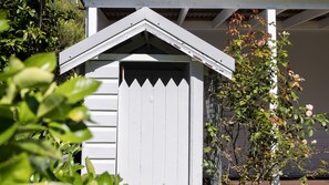 A white shed with a peaked roof and a white picket fence.