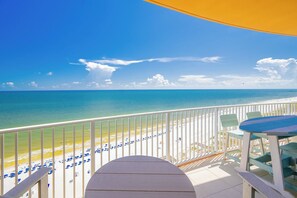 A balcony with a view of a beach, a table, and chairs. - Phoenix Gulf Towers 1803 | Gulf-Front 3BR  Pool, Lazy River & Beach (Orange Beach)