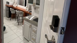 Eine kleine Küche mit Spüle, Hocker und Mikrowelle.