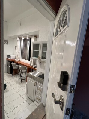 A compact kitchen with a sink, stools, and a microwave. - 1 bedroom suite #3 with Carenage view (Saint George's)