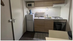 A compact kitchen with a microwave, stove, refrigerator, and sink. - 🌞 Rent Mobil-Home all comfort - Near Lac de Sainte-Croix 🌿 (Sainte-Croix-du-Verdon)