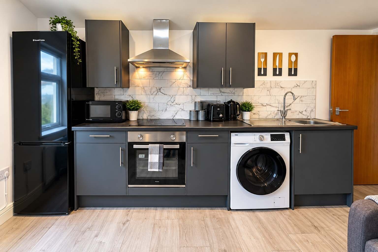 A modern kitchen with a refrigerator, oven, microwave, and washing machine.