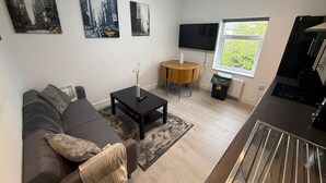 A modern living room with a sofa, coffee table, and artwork on the wall. - Sleek 1BR Flat  Perfect Getaway (Cardiff)