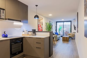 Eine moderne Küche mit integrierten Geräten, ein Essbereich mit Blick und ein Wohnraum mit Pflanze und Kunstwerken.