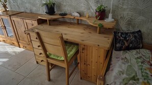 A wooden desk with a chair, a bed with a floral bedspread, and a wall with a leaf pattern. - Vacation apartment Waldbronn 1 person (Waldbronn)